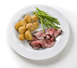 Roast with beef potatoes and asparagus on a white background