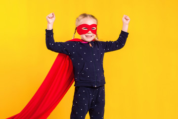 Superhero little girl in a red raincoat and a mask