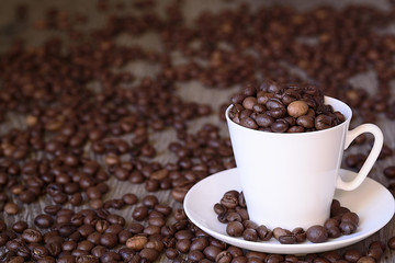 Coffee concept: fried coffee beans in porcelain white coffee cup