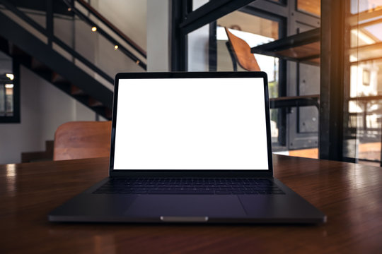 Mockup image of laptop with blank white screen on wooden table in modern loft cafe