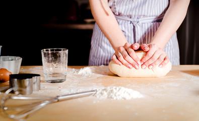Fototapeta na wymiar Woman's hands knead dough on a table