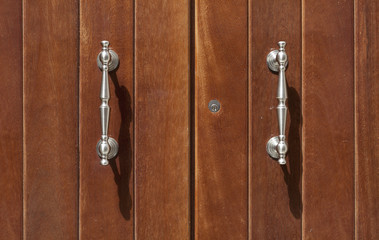 two silver vintage door knockers on a wooden door
