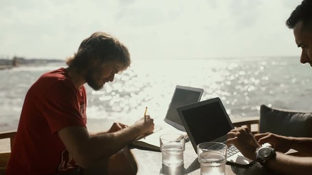 Two men works sitting in outdoors cafe