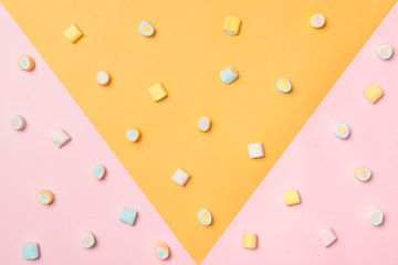 Top view of the pastel marshmallows on a pink and yellow background. Minimal style.