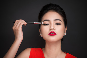 Obraz premium Close up of hand of asian woman applying eyeshadow on female eyelid.