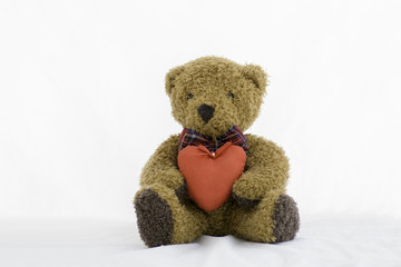 Brown teddy bear with red heart on a white background