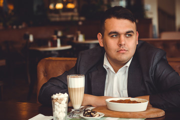 Young plus size with eating croissant and drink coffee , alone concept or lonely in big city life. Image of overweight businessman at downtown sit at restaurant