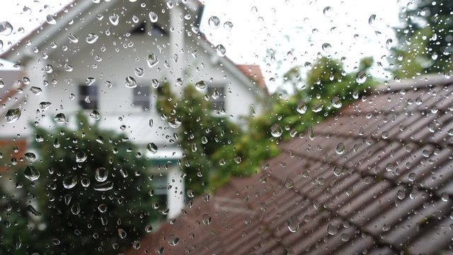 Rain drops on window glass with view to the neighbor house