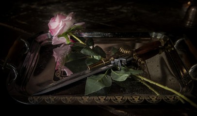 Rose and weapons. Stiletto with a rose on a tray.