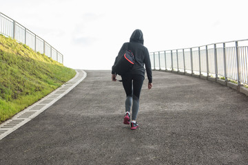 A woman in sportswear climbs the hill