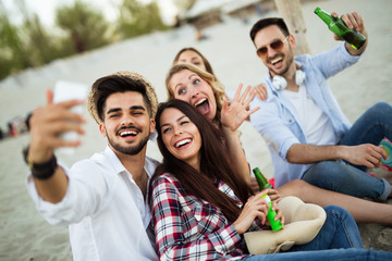 Happy young group of people taking selfies on beach