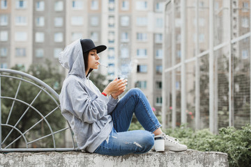 sporty swag girl in town smoking cigarrete and drinking coffee