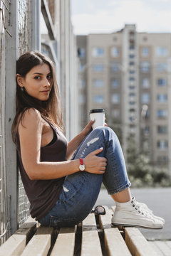 cute nice girl sitting nearby fence and drink coffee