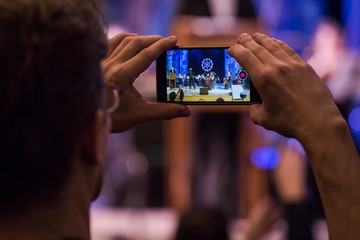 Man makes photo and video on smartphone on concert closeup