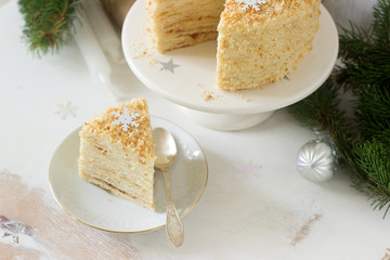 A piece of Napoleon cake in Christmas or New Year decoration on a light background. Rustic style.