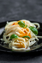 Spaghetti with sweet and sour sauce and basil leaves close-up..