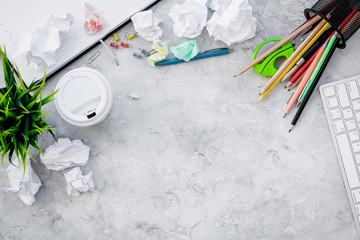 Chaos in office. Desk covered with crumpled paper and scattered stationery. Grey background top...