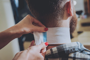 Master cuts hair and beard of men, hairdresser makes hairstyle for a young man. Hipsters