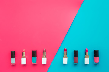 Decorative cosmetics concept. Lipsticks assorted colors and nail polish on red and blue background top view copyspace