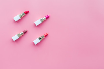 Lipsticks assorted colors on pink background top view copyspace