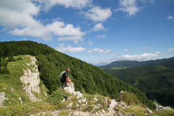 Hiker sits on mountain slope, Vado di Sole, National Park Gran Sasso and Monti della Laga, summer 