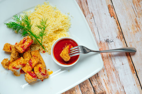 Tofu roasted wheat porridge and tomatoes. White plate on a wooden background.