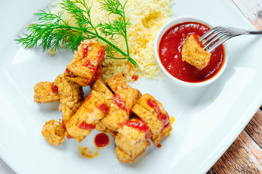 Tofu roasted wheat porridge and tomatoes. White plate on a wooden background.