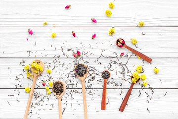Aromatic tea. Wooden spoons with dried tea leaves, flowers and spices on white wooden background top view