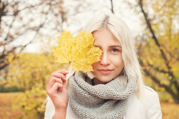 Beautiful Autumn Woman with Yellow Autumn Leaves on Fall Nature Background
