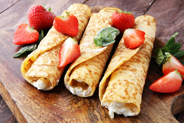 Crepes with jam, berries and sugar powder. Homemade pancakes, delicious breakfast.