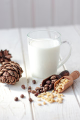 Cedar milk with pine nuts over white wooden table.
