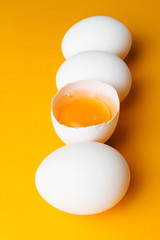 White eggs and egg yolk on the yellow background