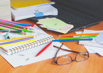 Glasses on the background of colored pencils and paper. The clutter on the desktop.