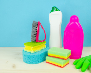 Set of cleaning and washing equipment isolated on wooden table against blue  background
