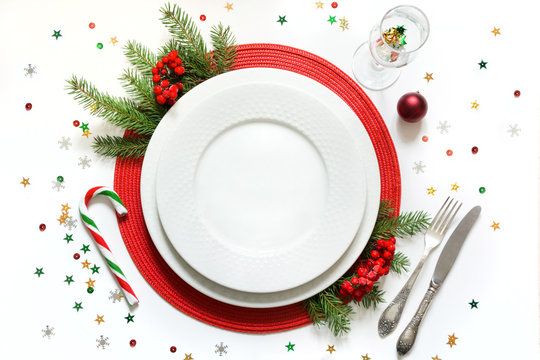 Christmas Table Setting With White Dishware, Silverware And Red Decorations On White Background. Top View.