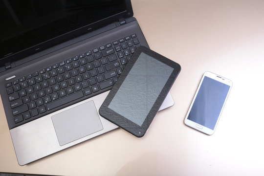 Picture of keyboard with a phone and tablet lying above it