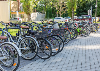 Fototapeta na wymiar Row of bicycles standing in the parking lot near the park. Sport and healthy lifestyle concept