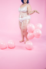 Plus size model in front of pink background with balloons