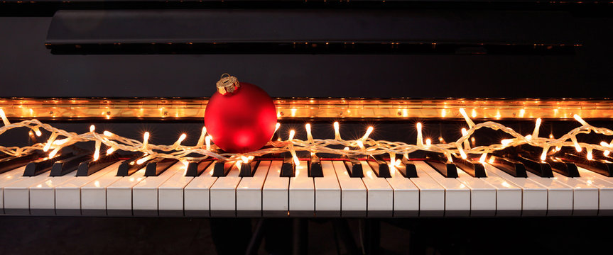 Christmas ball and lights on a piano keyboard, front view