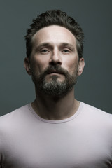 Fototapeta premium Fabulous at any age. Portrait of 40-year-old man standing over dark gray background. Close up. Classic style. Scar on forehead. Studio shot