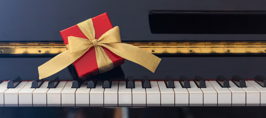 Red gift box on piano keyboard, front view