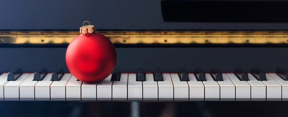 Red Chritmas ball on piano keyboard, front view