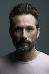 Fototapeta premium Fabulous at any age. Portrait of 40-year-old man standing over dark gray background. Close up. Classic style. Scar on forehead. Studio shot