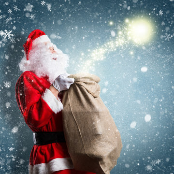 Weihnachtsmann mit Geschenkesack und Magie vor Winterhintergrund