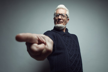 Guilty, know your place concept. Portrait of 60-year-old man standing over gray background and accusing you. Close up. Copy-space. Studio shot