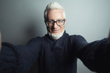 Fabulous at any age. Self-portrait concept. Eyewear concept. Portrait of a handsome mature man looking at camera in his hands. Close up. Studio shot