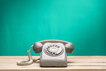 Vintage old telephone on wood table with turquoise wall background