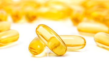 Fish oil capsules with omega 3 and vitamin D on white background