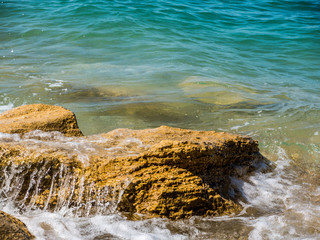 sea blue waves and surf breaking on coastal rocks. turquoise sea water and rocks in a Sunny day