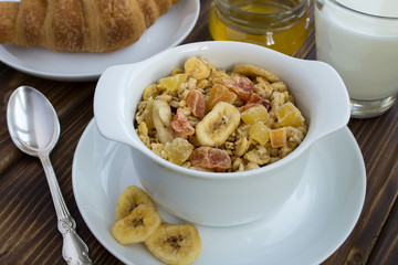 Muesli in the white plate on the wooden background